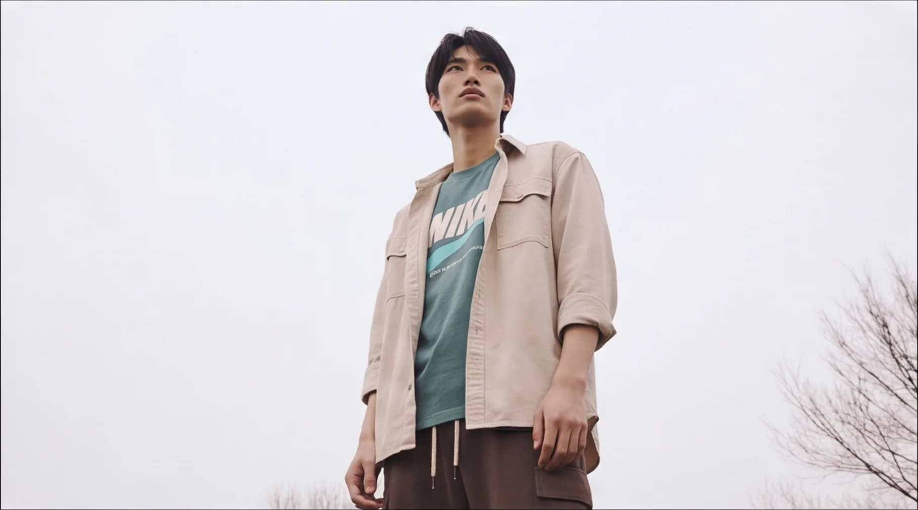 A man in an overshirt and Nike tee standing in a field, the kind of item resellers list