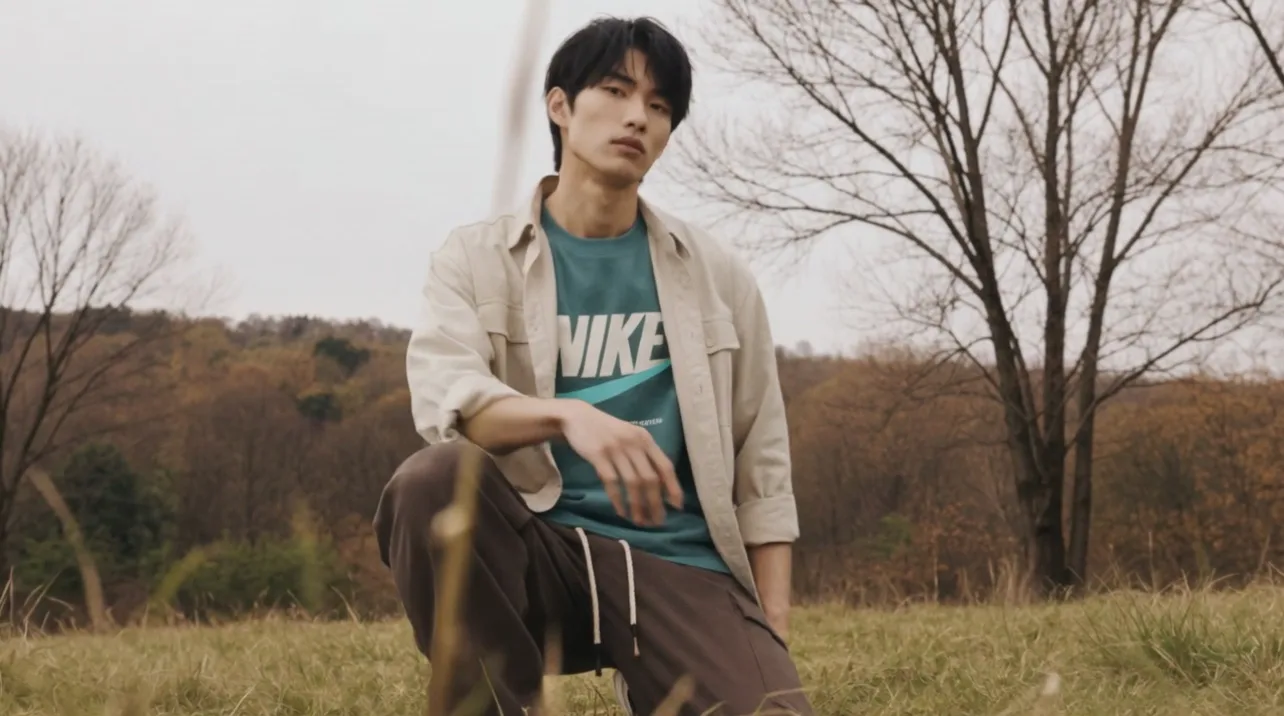 A person in a Nike tee and overshirt kneeling in a field, the kind of item a reseller lists